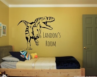 May include: A yellow bedroom with a wooden bed, a dinosaur wall decal, and the text "Landon's Room" on the wall.