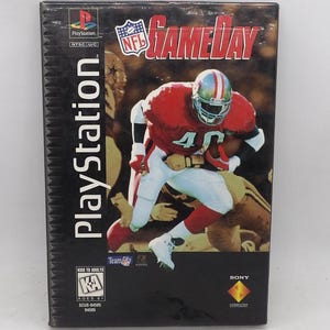 May include: A PlayStation video game case for NFL GameDay featuring a football player in a red jersey and white pants running with a football. The cover includes the NFL GameDay logo, the PlayStation branding, and a Kids to Adults rating symbol.