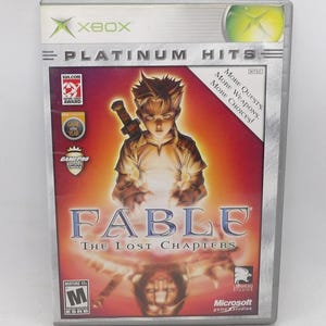 May include: Fable: The Lost Chapters Xbox game case. The cover features a young character with a sword, set against a fiery background. The case is labeled "Platinum Hits" and includes the Xbox logo and ESRB rating.