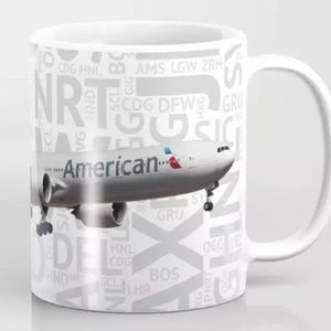 May include: White ceramic mug with a white airplane graphic and the text "American" on the side. The mug is covered in a pattern of airport codes, including NRT, CDG, DFW, and GRU.