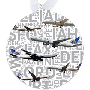 May include: A white round ornament with a repeating pattern of airport codes and the word "United" in black. Five United Airlines airplanes are flying over the pattern.