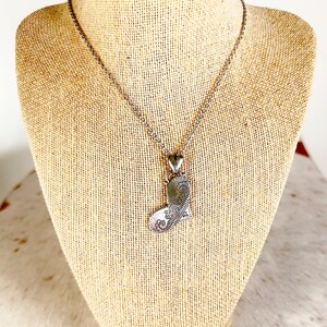 May include: A silver necklace with a detailed heart pendant. The heart is intricately designed with a floral pattern.