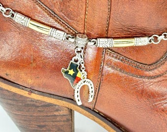 May include: A brown leather boot with a silver and gold chain with a Texas flag and horseshoe charm attached.