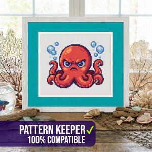 以下が含まれることがあります： 怒った赤いタコのクロスステッチアート。青い泡があり、白とターコイズのフレームに入っています。画像は、金魚鉢、貝殻、ミニチュア灯台など、航海をテーマにした装飾が施された木製の表面に表示されます。「PATTERN KEEPER 100% COMPATIBLE」というテキストが下にあります。