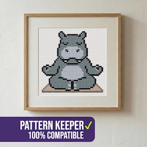 May include: A framed cross-stitch pattern of a gray hippo in a seated yoga pose. The hippo is on a beige mat, with its eyes closed and arms outstretched. The frame is light brown, and the image includes the text "PATTERN KEEPER 100% COMPATIBLE".