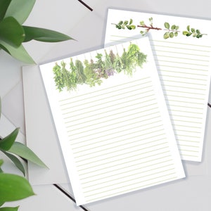 May include: Two sheets of lined paper with a green botanical illustration at the top of each sheet. The top illustration features a sprig of leaves and a branch with small green leaves. The bottom illustration features a row of green herbs hanging from a string.
