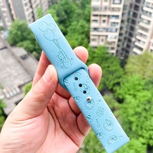 May include: Light blue silicone watch band with a Winnie the Pooh design. The band features a cartoon image of Winnie the Pooh holding balloons and a pattern of honey pots, bees, and honeycombs.