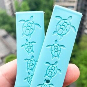 Puede incluir: Dos correas de reloj azul claro con un patr&oacute;n repetido de tortugas marinas. Las correas est&aacute;n hechas de un material suave y flexible y tienen un acabado liso y mate.