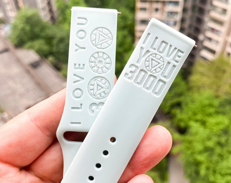 May include: Two light gray watch bands with the text "I Love You 3000" and an Iron Man symbol.