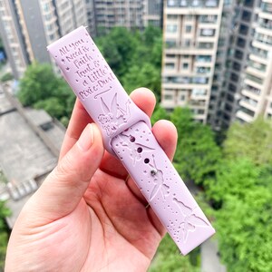 May include: A lavender silicone watch band with a Tinkerbell design and the text "All you need is Faith Trust & a Little Pixie-Dust".