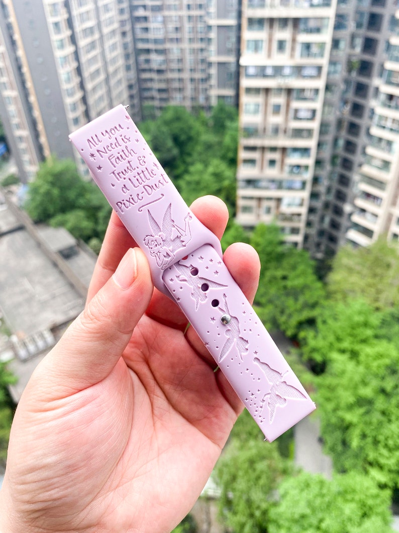 May include: A lavender silicone watch band with a Tinkerbell design and the text "All you need is Faith Trust & a Little Pixie-Dust".