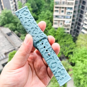 May include: A light blue silicone watch band with a leopard print design.