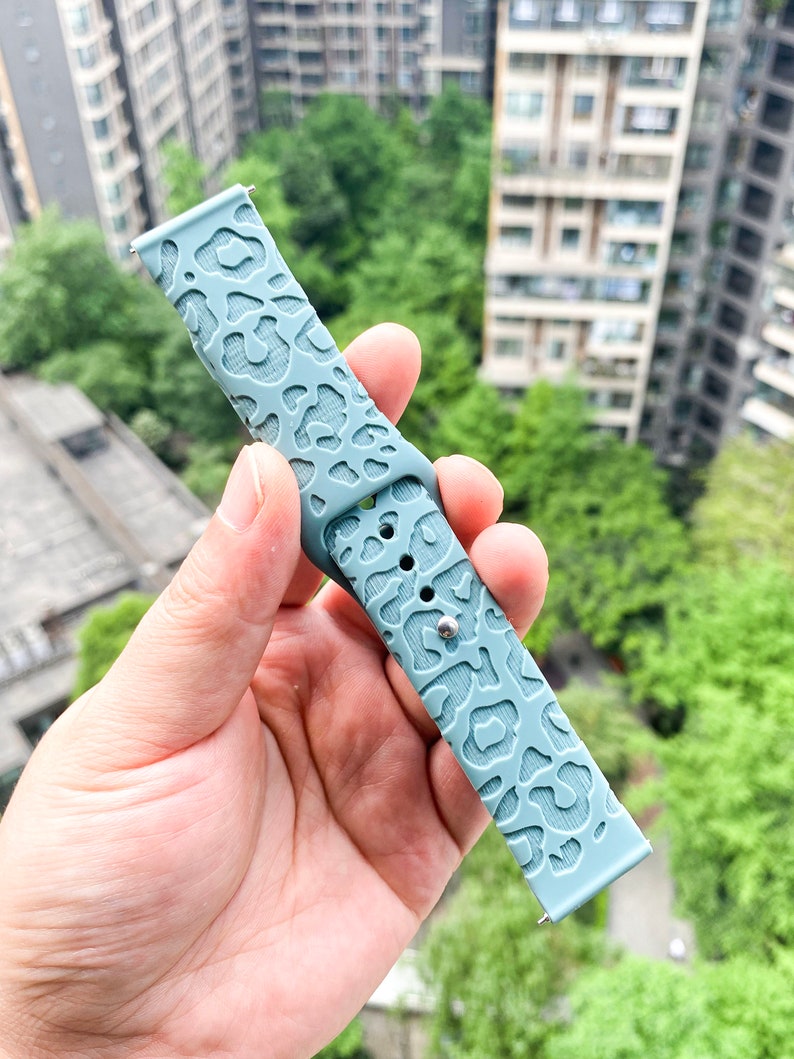 May include: A light blue silicone watch band with a leopard print design.