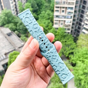 May include: A light blue silicone watch band with a leopard print design.