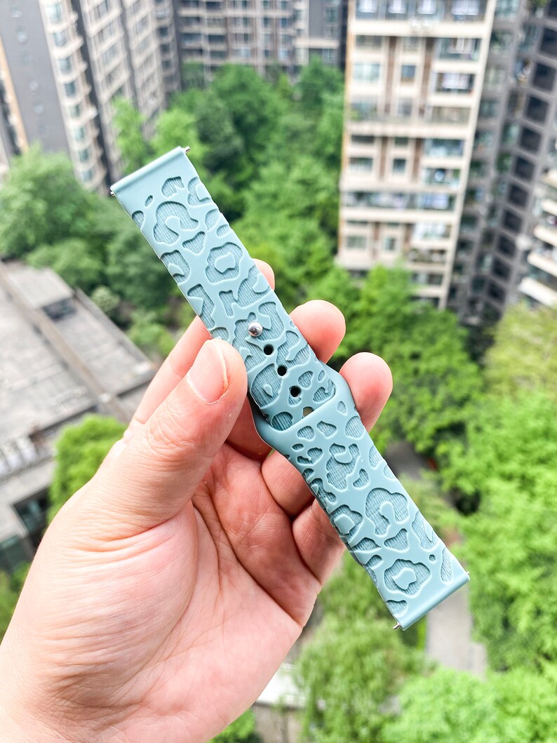 May include: A light blue silicone watch band with a leopard print design.