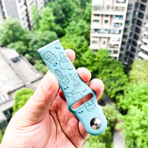 Puede incluir: Una pulsera de reloj de silicona azul claro con un dise&ntilde;o de cactus. La pulsera tiene una hebilla plateada.