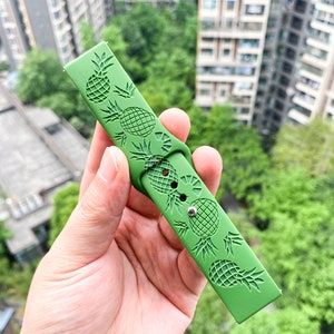 May include: Green silicone watch strap with a pineapple design.