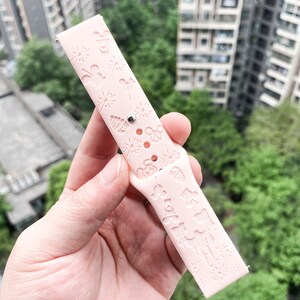May include: Pink silicone watch band with a white embossed design featuring Mickey Mouse, fireworks, and other Disney park icons.