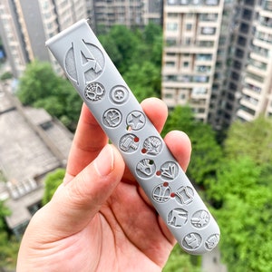 May include: A gray silicone watch band with a raised design of various Marvel characters, including Iron Man, Captain America, Thor, and Spider-Man. The band has the letter "A" for Avengers in the center.