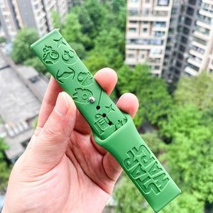May include: Green silicone watch strap with a Star Wars theme. The strap features various Star Wars characters and symbols, including R2-D2, Darth Vader, and the Millennium Falcon. The strap also has the words "Star Wars" embossed on it.