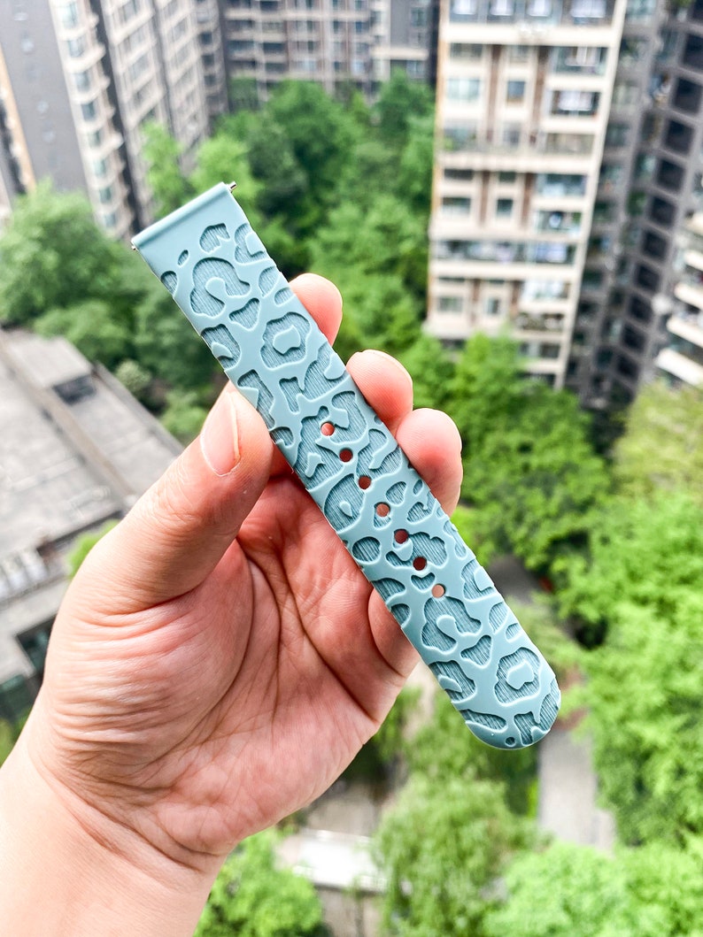 May include: A light blue silicone watch band with a leopard print design.
