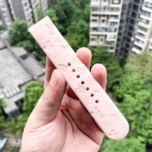 May include: A pink silicone watch band with a repeating pattern of Mickey Mouse, fireworks, and other Disney-themed icons.