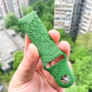 May include: Green silicone watch band with a sunflower pattern embossed on the surface. The band has a silver metal buckle.
