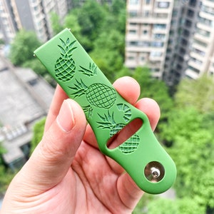 May include: Green silicone watch strap with a pineapple pattern. The strap has a silver metal buckle.