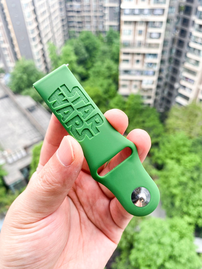 May include: Green silicone watch strap with the words "STAR WARS" embossed on the strap. The strap has a silver metal buckle.