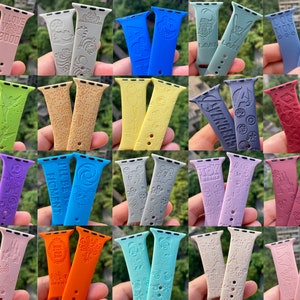 May include: A collection of 20 colorful silicone watch bands with various designs and text. The bands are all for Apple Watches and feature different patterns and phrases.