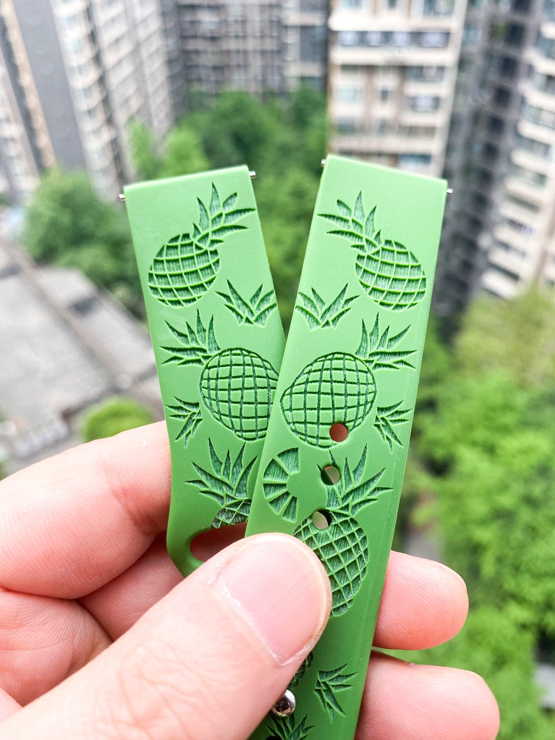 May include: Two green watch straps featuring a pineapple design. The straps are made from a soft, flexible material and have a textured finish.