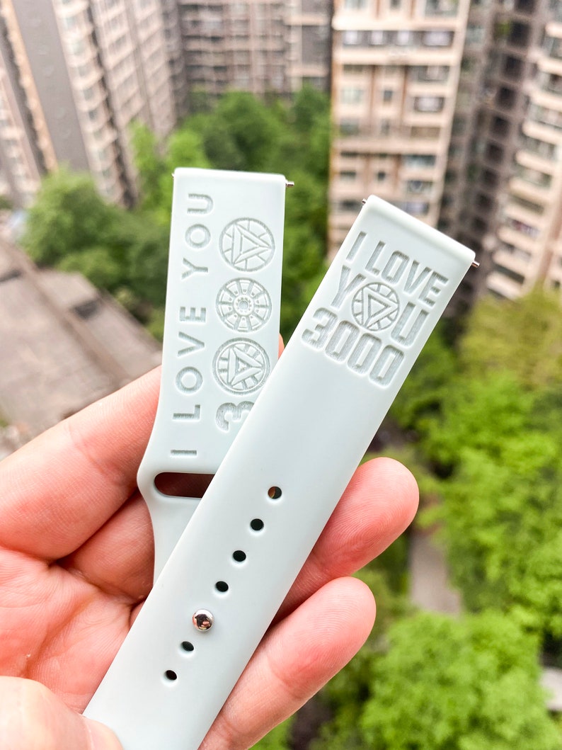 May include: Two light blue silicone watch bands with the words "I Love You 3000" embossed on them. The bands have a silver metal buckle and are designed for a smartwatch.