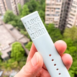 May include: A light blue watch band with the words "I love you 3000" and an Iron Man symbol embossed on it.