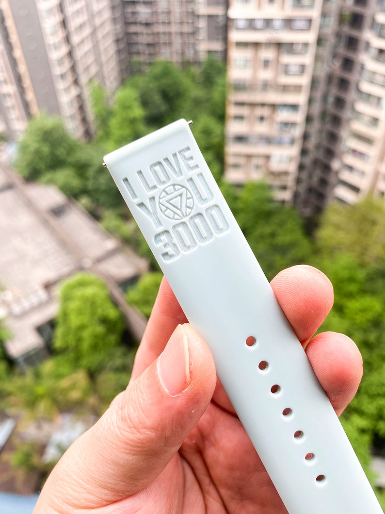 May include: A light blue watch band with the words "I love you 3000" and an Iron Man symbol embossed on it.