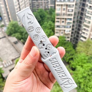 May include: Gray silicone watch band with the Avengers logo and various Marvel character symbols embossed on the band.