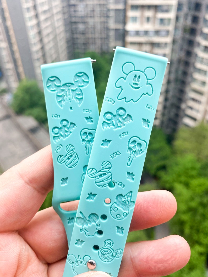 May include: Two turquoise blue silicone watch bands with a Halloween theme. The bands feature Mickey Mouse, ghosts, bats, and candy corn.