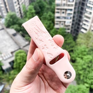 May include: A pink silicone watch band with a white embossed design of Cinderella's castle and other Disney characters.