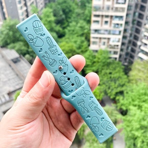 Puede incluir: Una correa de reloj de silicona azul claro con un dise&ntilde;o de cactus y plantas.
