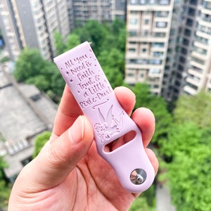 May include: A light purple silicone watch band with a silver metal clasp. The band has a Tinkerbell design and the text "All you *Need is *Faith *Trust & a Little Pixie-Dust".