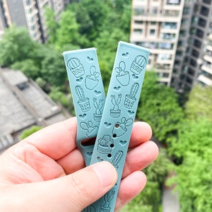 Puede incluir: Dos correas de reloj de silicona azul claro con estampado de cactus. Las correas tienen un patr&oacute;n de coraz&oacute;n y est&aacute;n dise&ntilde;adas para un reloj inteligente.