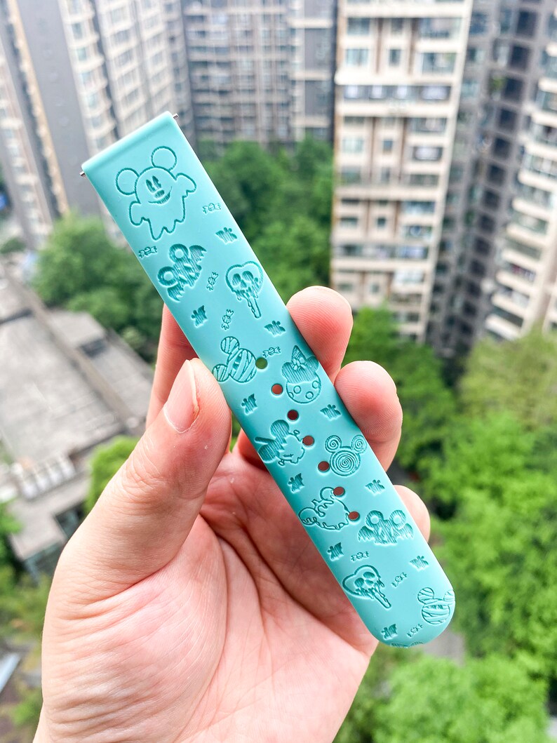 May include: A light blue silicone watch band with a Mickey Mouse and Halloween themed design. The band features various Mickey Mouse characters, ghosts, and other Halloween icons.