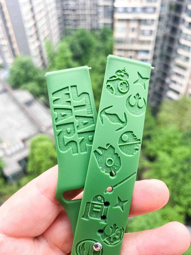 May include: Green silicone watch strap with a Star Wars theme. The strap features the words "Star Wars" and various Star Wars characters, including R2-D2, a lightsaber, and the Death Star.