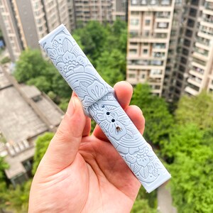 May include: A light blue watch band with a floral pattern. The band is made of silicone and has a smooth, soft texture.