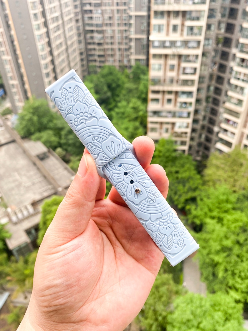 May include: A light blue watch band with a floral pattern. The band is made of silicone and has a smooth, soft texture.