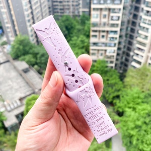 May include: A light purple silicone watch band with a Tinkerbell design. The band features a silhouette of Tinkerbell flying with stars and the text "All you need is faith, trust, and a little bit of pixie dust".