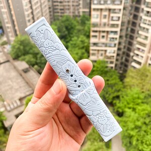 May include: A light blue silicone watch band with a floral pattern. The band is embossed with a delicate floral design.