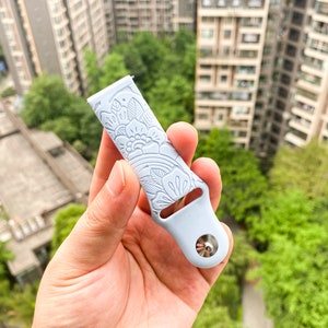 May include: A light blue silicone watch band with a white floral pattern. The band has a silver metal connector.