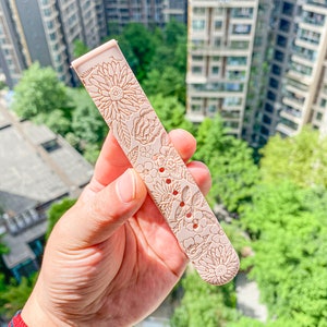 May include: A pale pink watch band with a floral pattern. The band is made of silicone and has a textured surface.