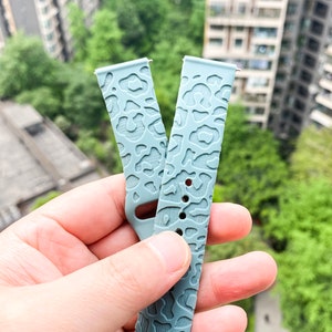 May include: Two light blue silicone watch bands with a leopard print design.