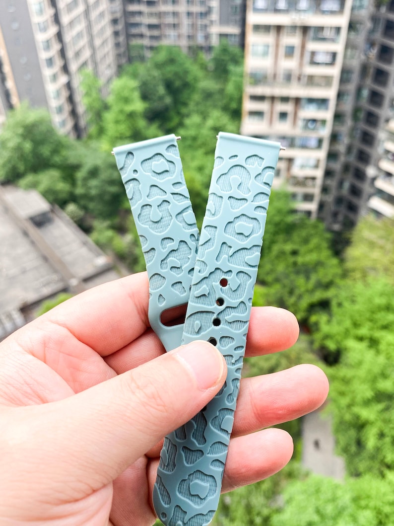 May include: Two light blue silicone watch bands with a leopard print design.